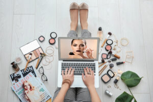 woman on laptop surrounded by beauty tools